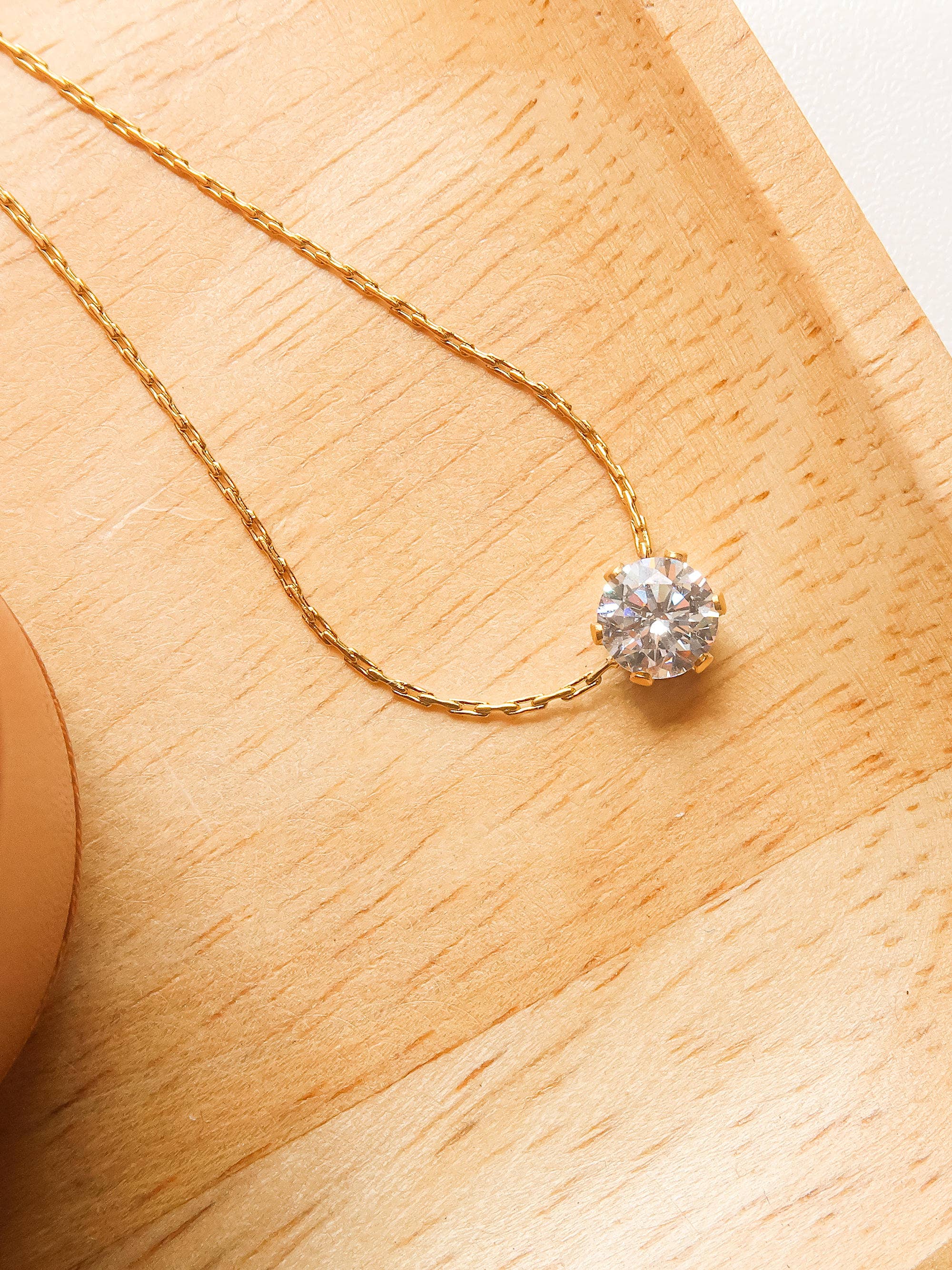 Gold necklace with a cz pendant on a wooden surface
