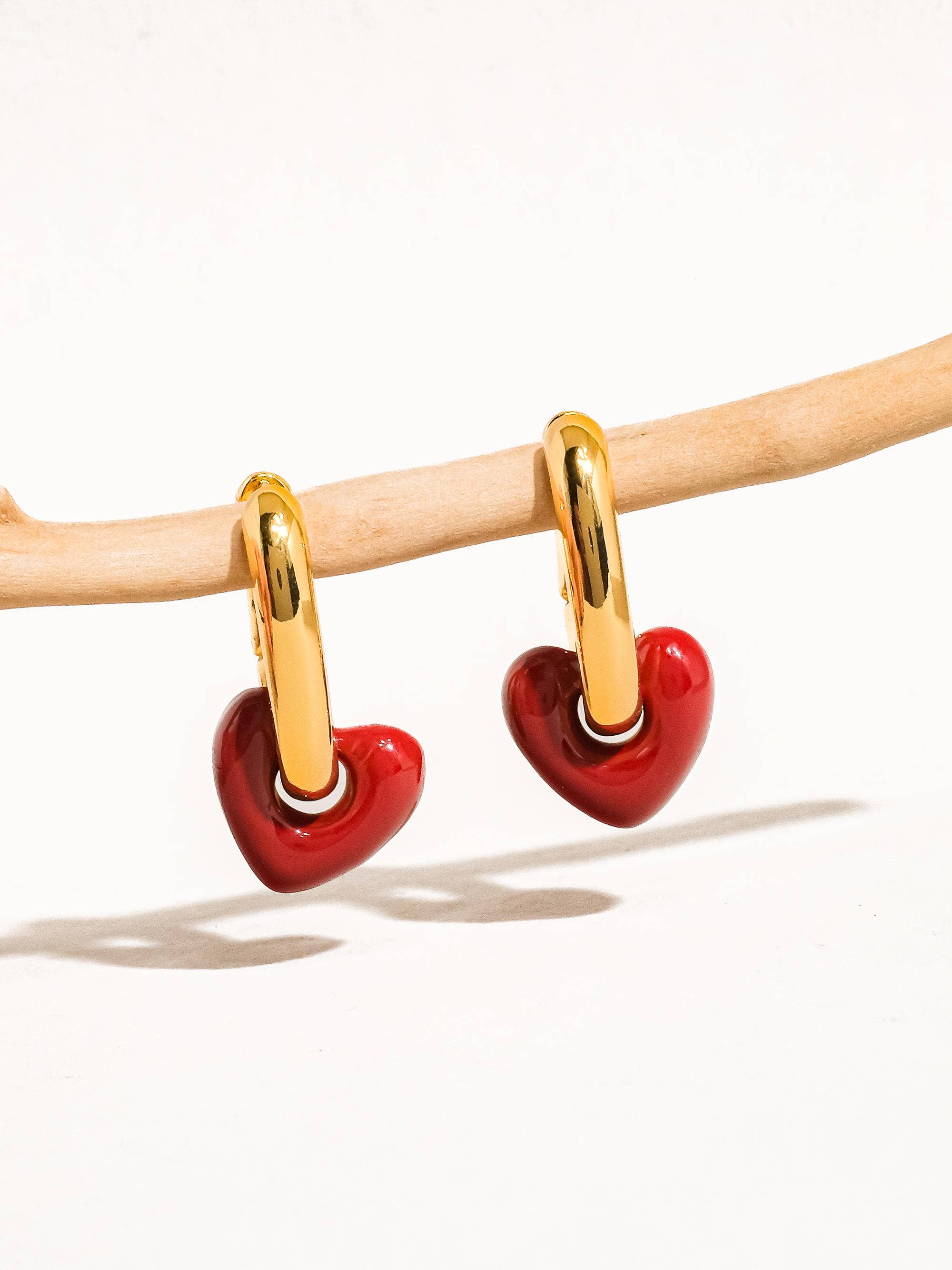 Heart-shaped earrings with gold loops on a white background