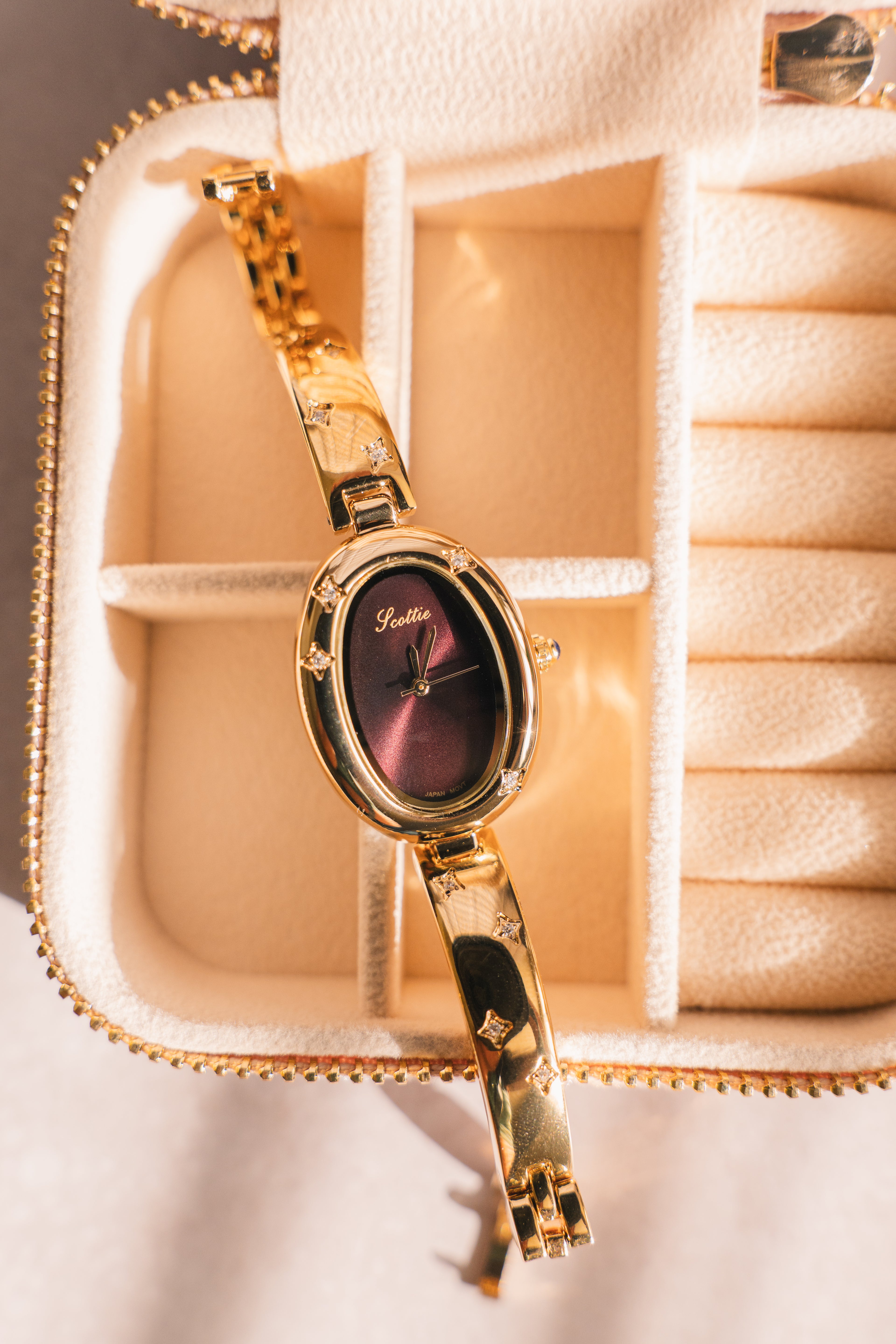Gold oval watch with star accents displayed in a cream jewelry travel case — Ligisol women's accessories