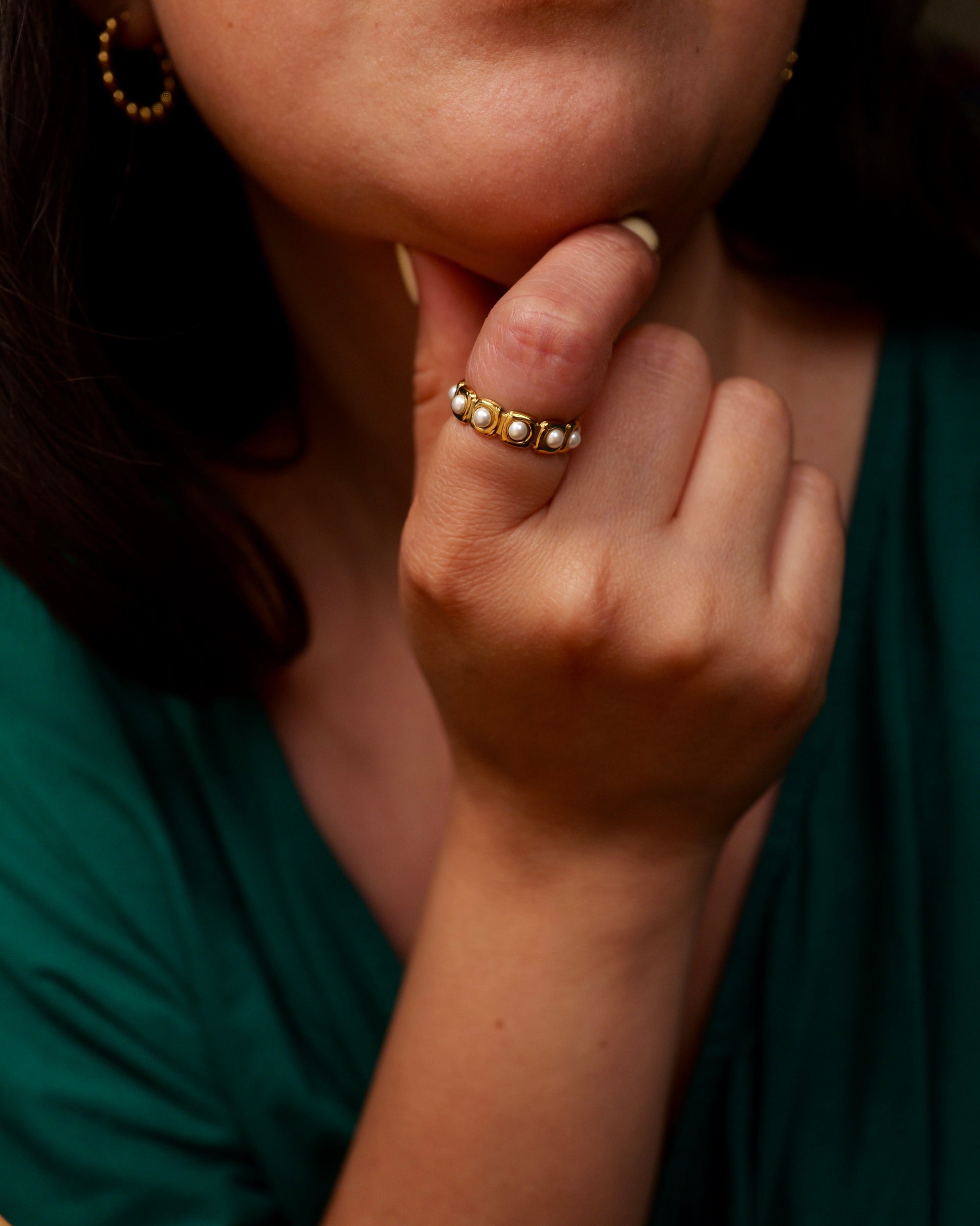Close-up of a person wearing a gold ring with a green top.