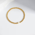 Izzy 18K gold stainless steel stretch bracelet featuring a single pearl among gold beads.