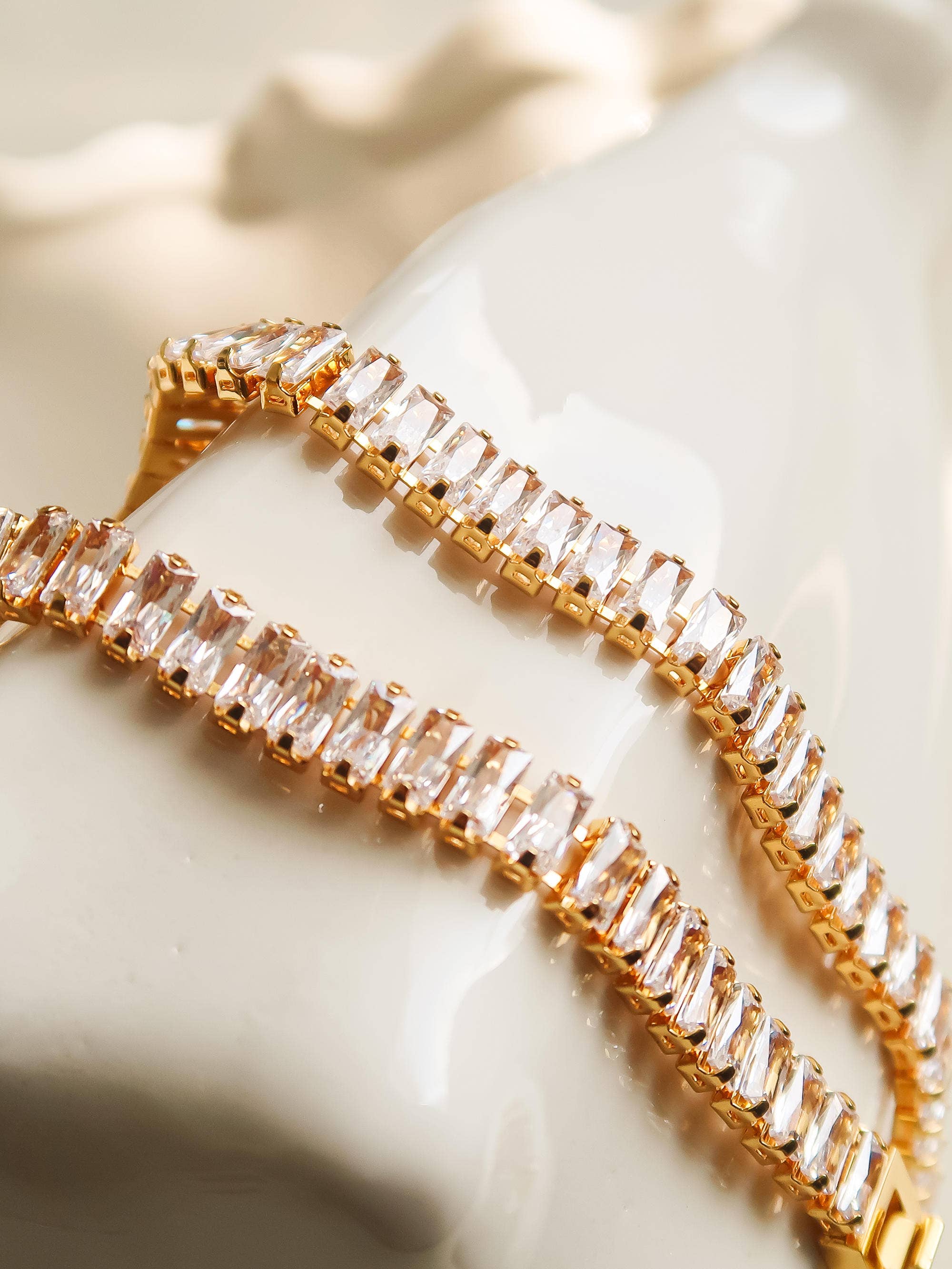 Gold bracelet with clear gemstones on a white surface