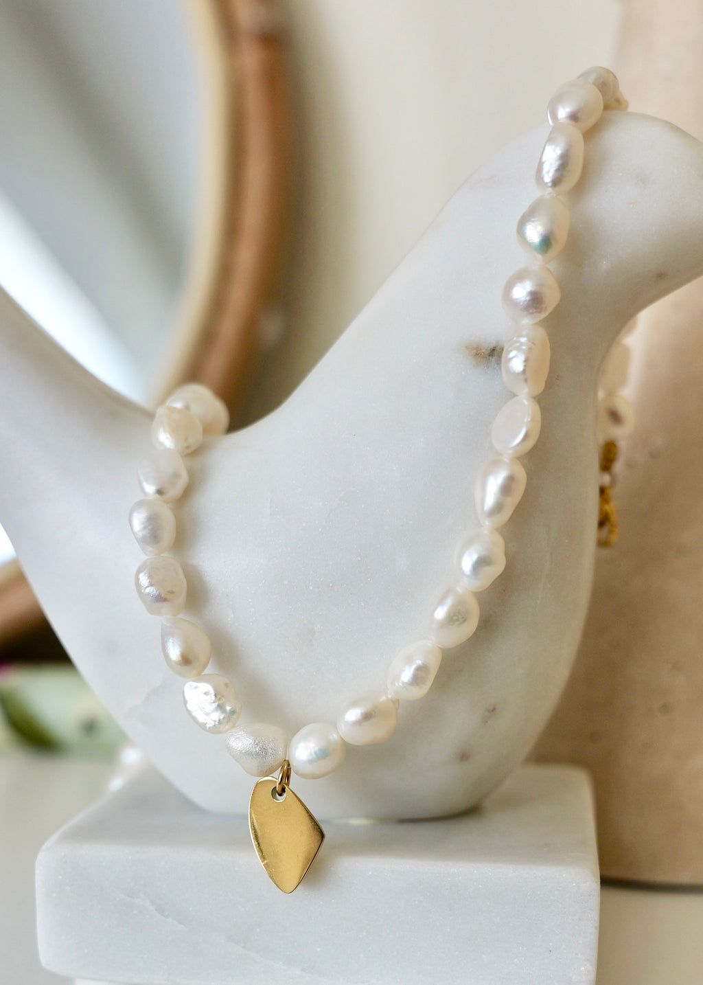 Pearl necklace with a gold tag on a marble surface